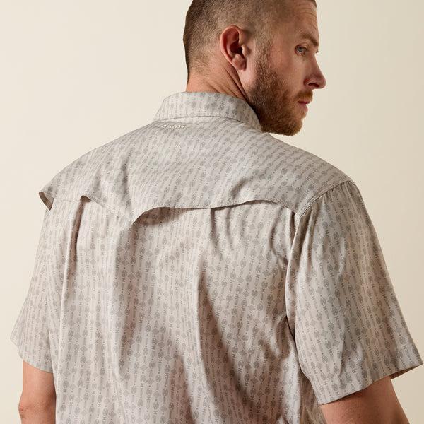 Man wearing a patterned short-sleeve shirt against a beige background