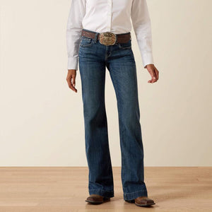 Person wearing blue jeans with a white shirt and brown belt on a beige background