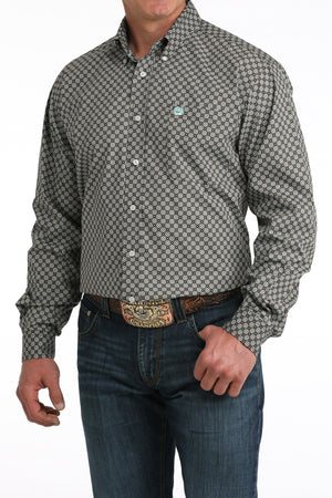 Man wearing a patterned long-sleeve shirt and jeans on a white background