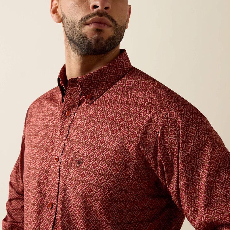 A close-up of a man wearing a long-sleeve button-down shirt with a textured geometric pattern in dark red and brown, set against a plain beige background.