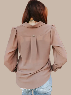 A woman wearing a mocha long-sleeve button-up blouse. 
