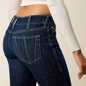 Person wearing blue jeans and a white long-sleeve top on a beige background