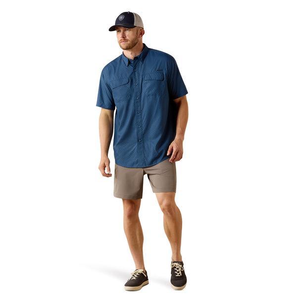 Man wearing a blue shirt, beige shorts, and a cap on a white background