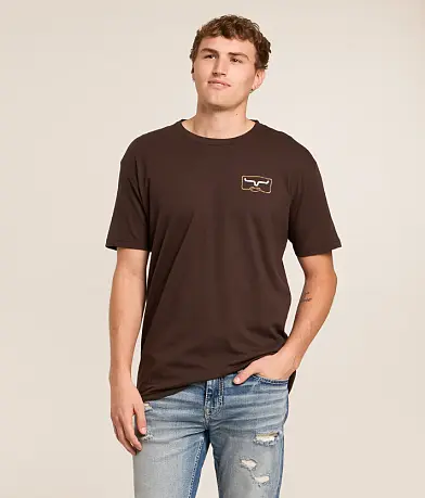 A man wearing a dark brown short-sleeve t-shirt with a small embroidered logo on the left chest. 