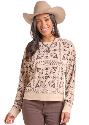 A woman wearing a beige and brown patterned long-sleeve knit sweater, a tan cowboy hat, and brown pants, photographed against a plain white studio background.