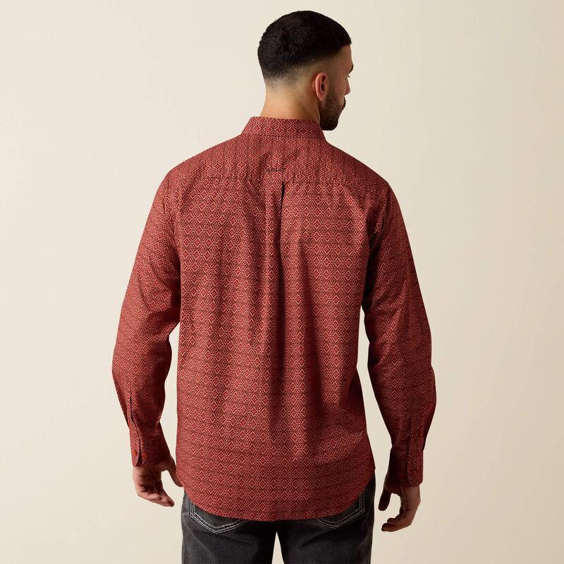 A man viewed from the back wearing a long-sleeve button-up shirt with a textured, geometric pattern in rust red and dark brown, paired with dark jeans against a plain beige background.
