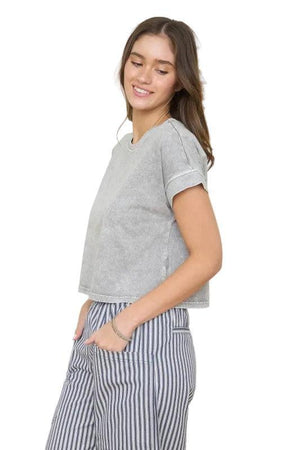 Woman wearing a brown short sleeve top.