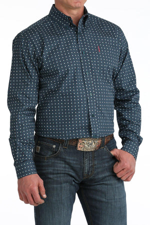 Man wearing a blue patterned shirt and jeans with a belt buckle.