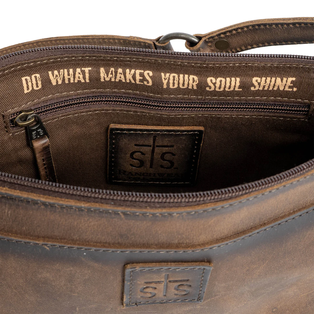 Brown leather bag with motivational quote and brand logo on a white background