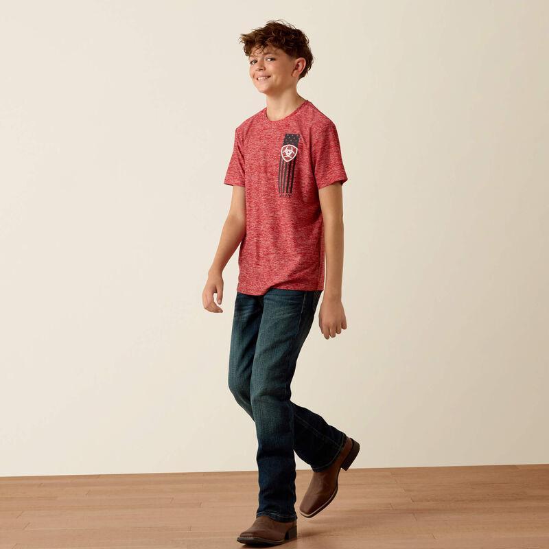 Child wearing a red t-shirt with a graphic design and dark jeans on a plain background
