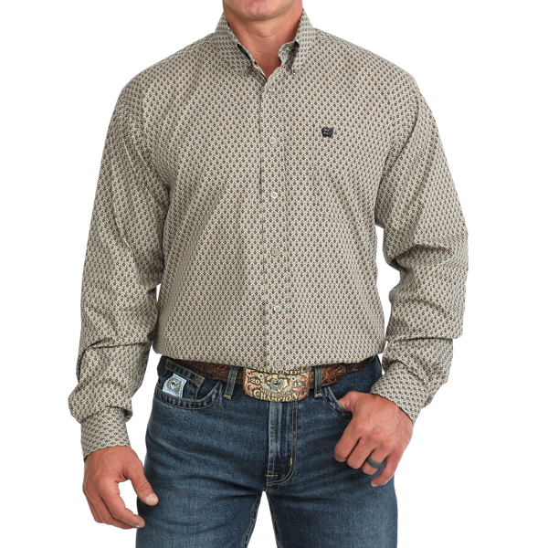 A man wearing a long-sleeve western-style button-down shirt with a small repeating geometric pattern in beige and black, paired with blue jeans and a brown belt.