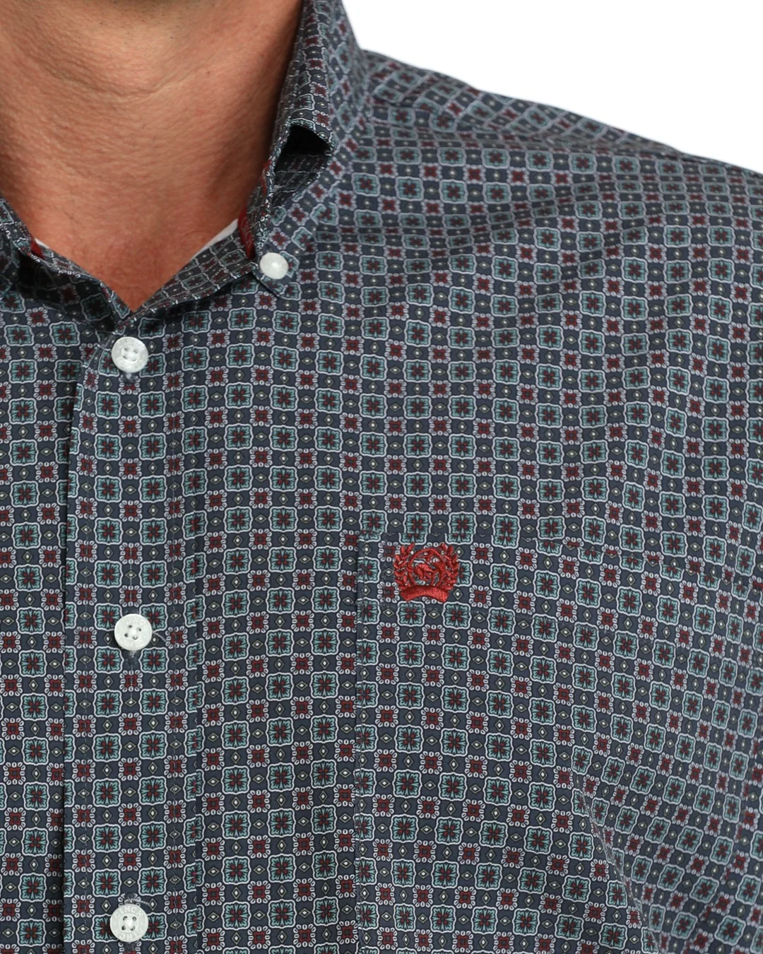 A man wearing a blue and burgundy micro-patterned western long-sleeve button-down shirt with a small red embroidered logo on the chest 