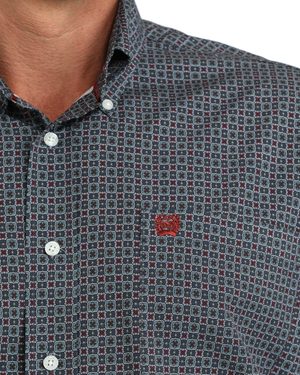 A man wearing a blue and burgundy micro-patterned western long-sleeve button-down shirt with a small red embroidered logo on the chest 