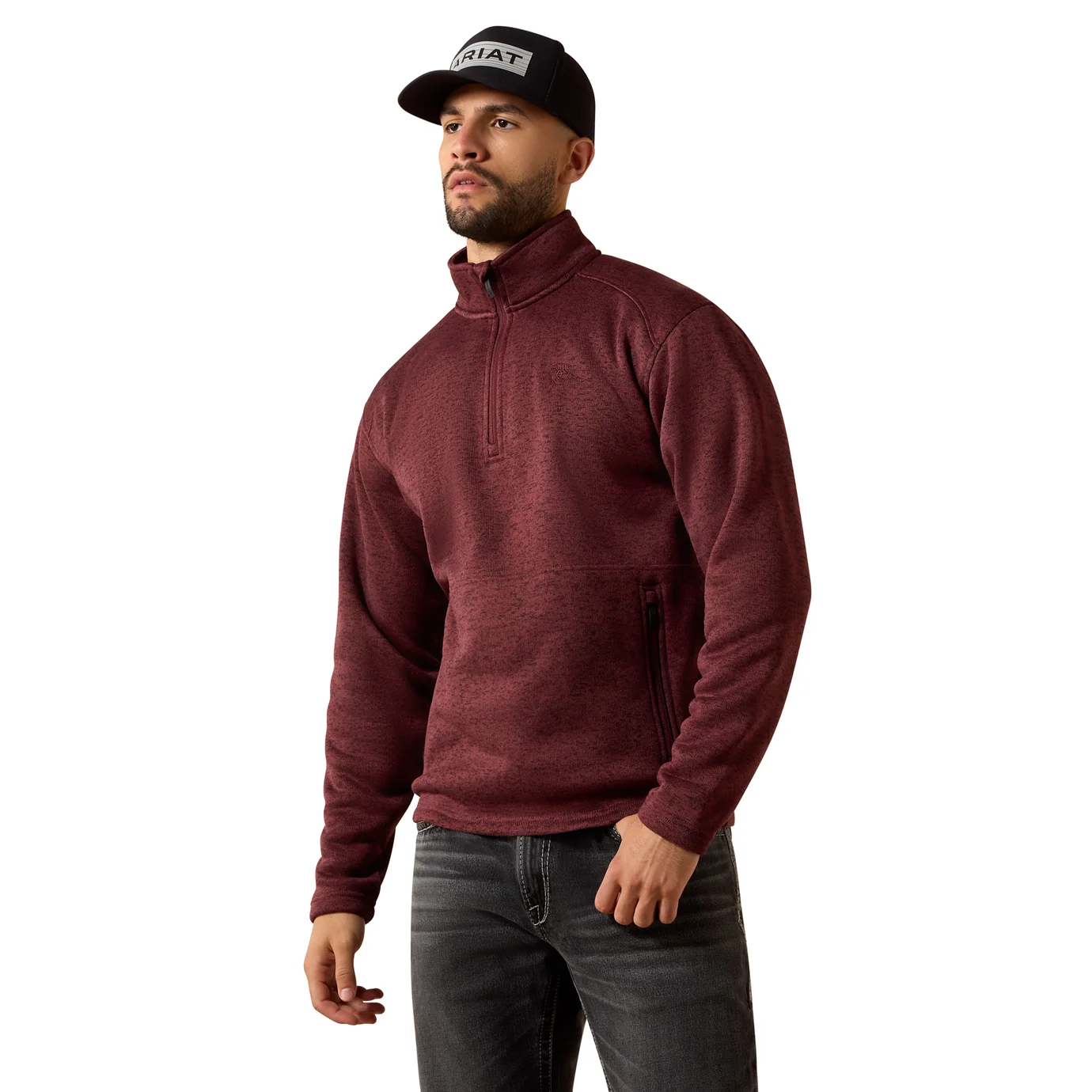 Man wearing a maroon pullover, black cap, and jeans on a white background