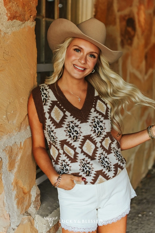 Cream colored Sleeveless sweater vest with brown trim and geometrical Aztec pattern. 