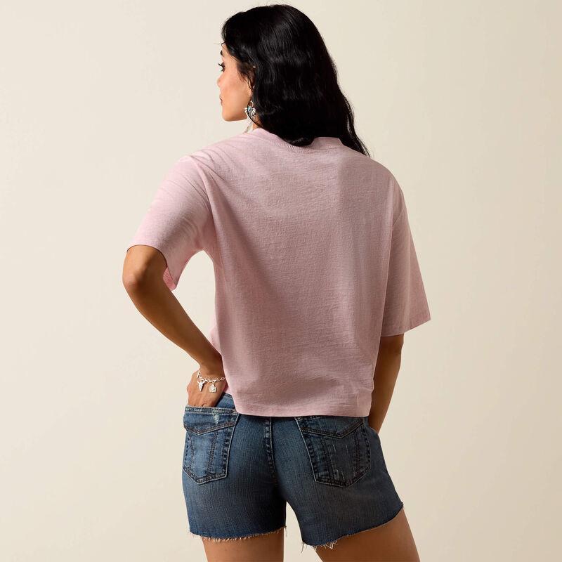 Woman wearing a pink shirt and denim shorts on a beige background