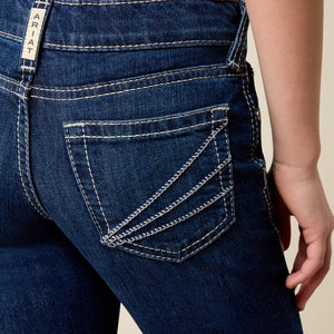 Close-up of the back of dark blue denim jeans with white contrast stitching, showing the pocket detail and a vertical brand tab reading ARIAT.